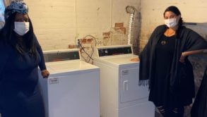 2 women standing by laundry machine