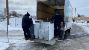 2 man unloading a truck with washing machines in winter