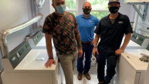 3 men standing in a laundry room with masks on