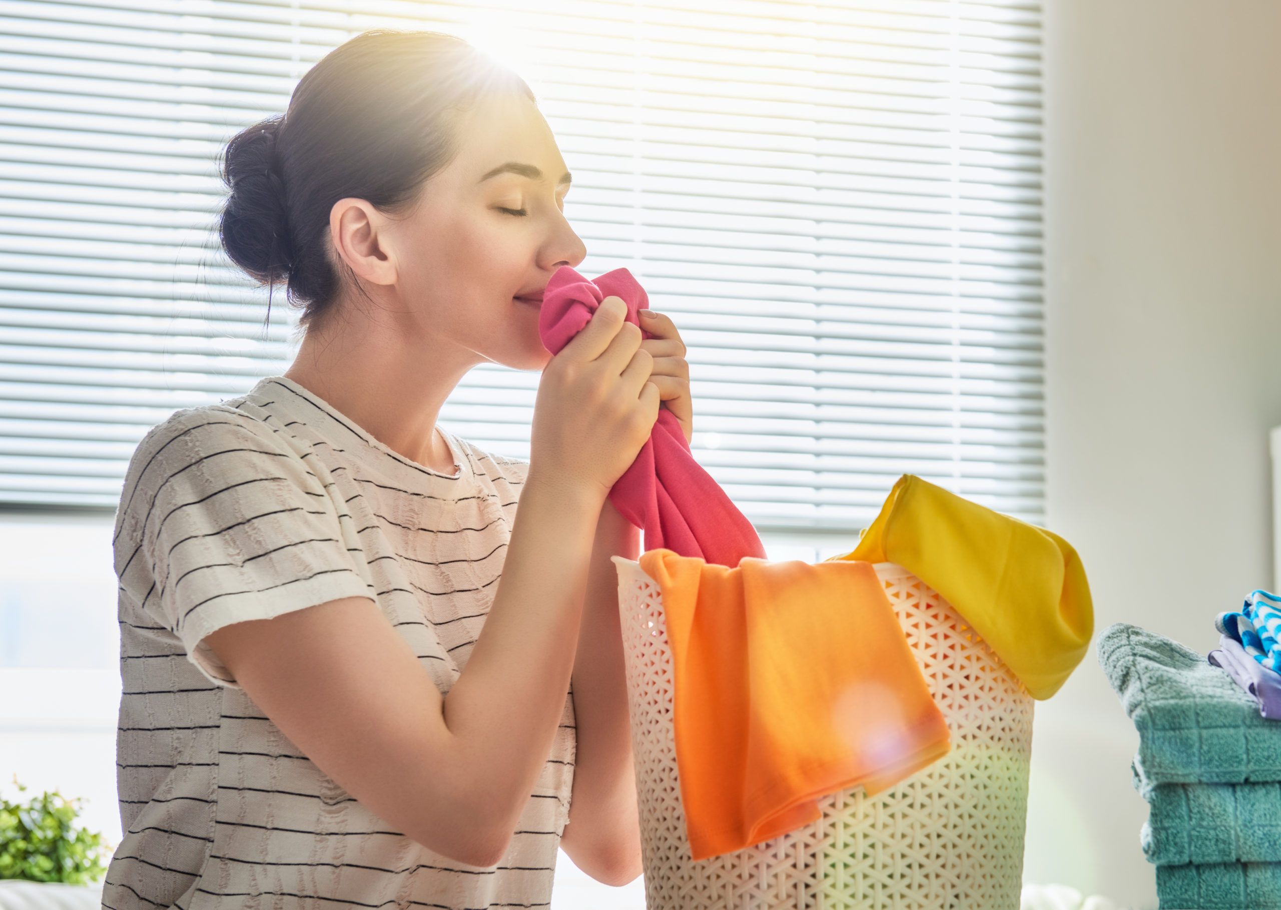 Beautiful,Young,Woman,Is,Smelling,Clean,Clothes,And,Smiling,While