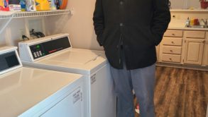 man standing near 2 washing machines